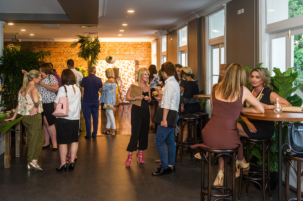 Guests mingling near windows and high tables inside Transcontinental Hotel