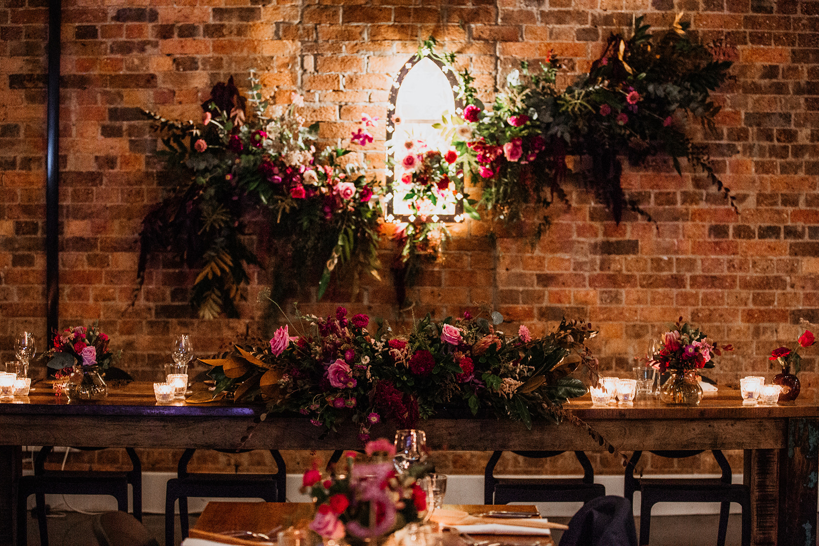 Hanging floral installation above reception tables in a character filled wedding space