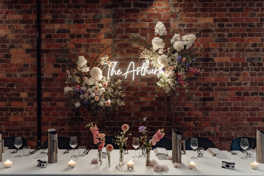 Styled wedding reception table with floral feature and brick wall at Transcontinental Hotel