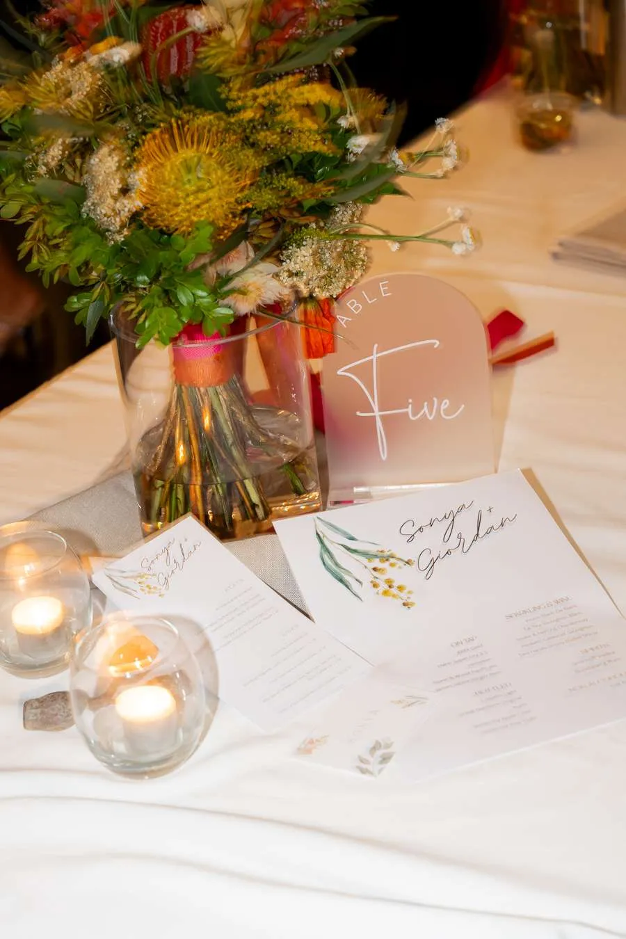 Seasonal wedding table details with flowers, candles and printed menus in Brisbane Caption: Colour, candlelight and floral texture can shift the mood between summer freshness